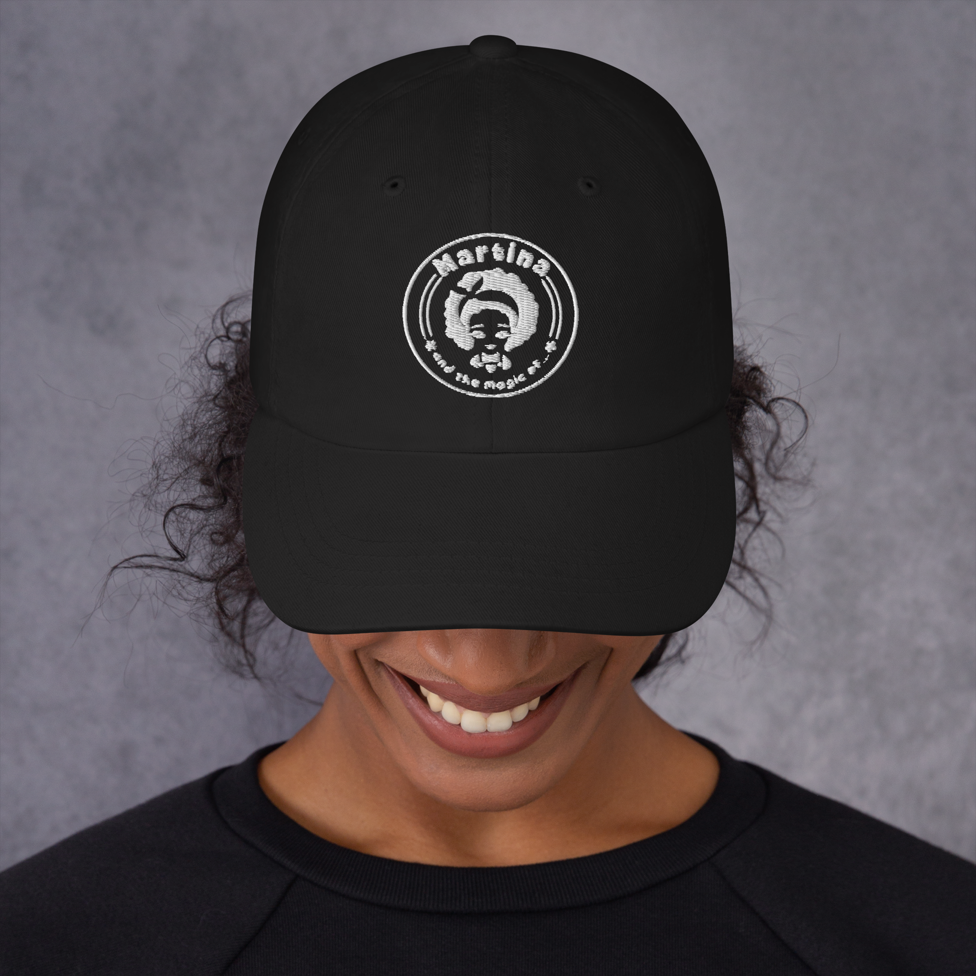 Person smiling while wearing a black cap with a Spartan helmet logo.